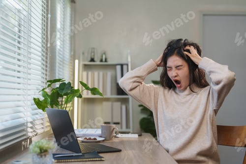 Preview: Young asian freelancer yawning and touching her hair, exhibiting signs of stress and fatigue while w