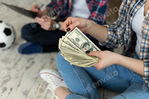 Preview: Young couple counting money while sitting on floor in new apartment