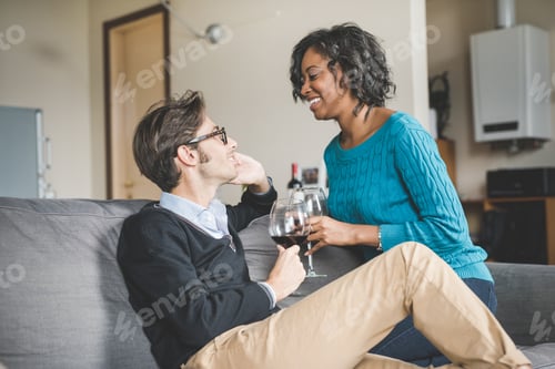 Preview: Young handsome mixed race couple in their house having a glass of red wine