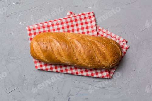 Preview: freshly baked bread with napkin on rustic table top view. Healthy white bread loaf isolated