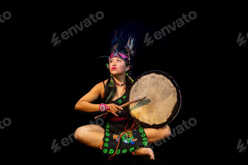 Preview: Young female with traditional dress dancing with trappings with feathers and drum