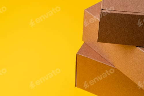 Preview: Beige cardboard boxes on yellow background, close up