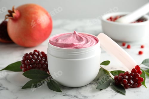 Preview: Fresh pomegranate and jar of facial mask on white marble table, closeup. Natural organic cosmetics