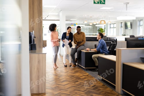 Preview: Diverse businesspeople in office talking and laughing