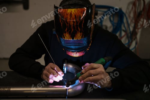 Preview: Man using welding machine in His garage. He is repairing a metal motorcycle part. Jobs and hobbies