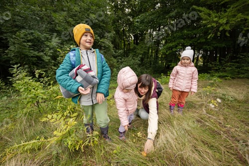 Preview: Mother and children searching mushrooms in the wild forest.