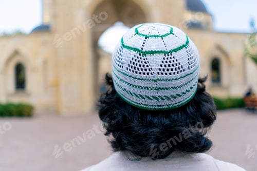 Preview: Back shot of Arab man entering the inner courtyard a mosque on a terrace with Islamic ornamentation