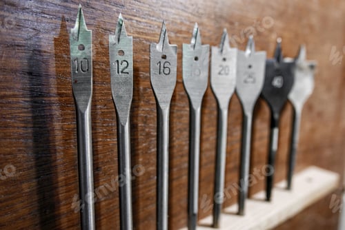 Preview: Selective focus photo of a set of spade drill bits in carpenter workshop.