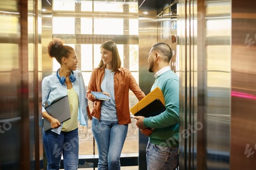 Preview: Diverse work colleagues using elevator in modern coworking office