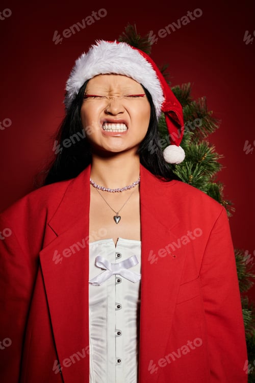 Preview: Festive celebration with a joyful Asian woman wearing a Christmas hat and vibrant red jacket