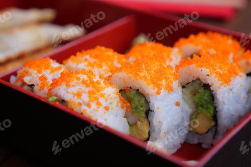 Preview: Sushi rolls with orange toppings served in a red box