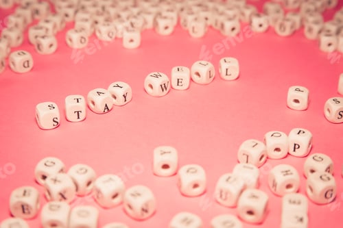 Preview: White dices over a pink pastel background with stay well message, wellness and life concepts