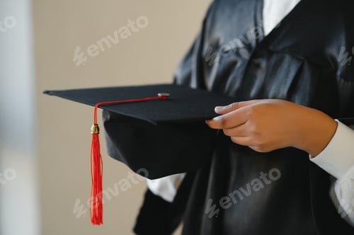 Preview: Happy Indian university student in graduation gown and cap holding diploma certificate.