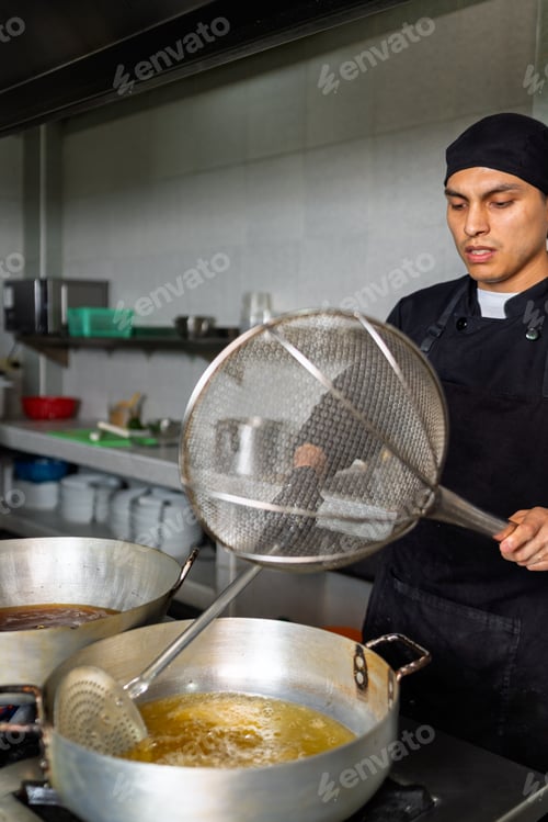 Preview: Peruvian chef frying fish in a wok in a restaurant kitchen