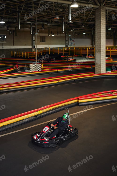Preview: african american man in helmet in go-kart inside of indoor karting track, go-cart active hobby