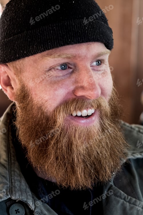 Preview: Portrait of smiling bearded man with light brown hair, wearing black beanie.