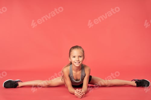 Preview: Cute sporty girl doing splits against red background