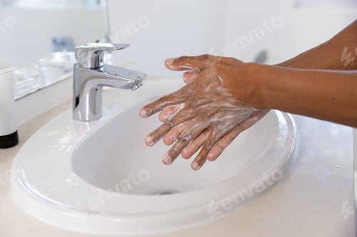 Preview: Close up of biracial man washing hands in bathroom at home