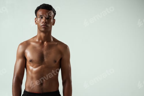 Preview: After workout. Portrait of young shirtless muscular african man looking at camera while standing