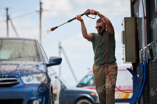 Preview: Confident man washing his car on self car-washing station.