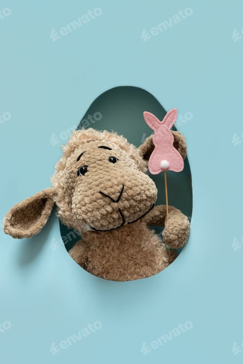 Preview: Toy Sheep with Bunny Decoration on blue Background. Playful Easter Composition