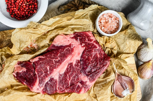 Vista previa: Raw beef steak on a chopping Board. Organic farm meat. Gray background.
