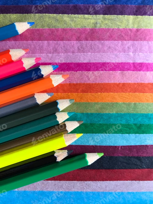 Preview: Color pencils at an angle on multicoloured tissue paper in horizontal lines. Flatlay photography