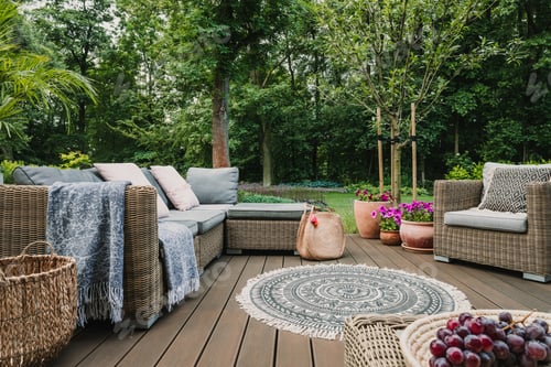 Preview: Garden patio decorated with Scandinavian wicker sofa and coffee table