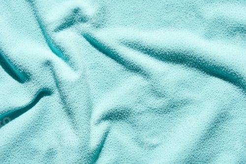 Preview: Textured teal fabric surface with soft wrinkles and subtle light reflections