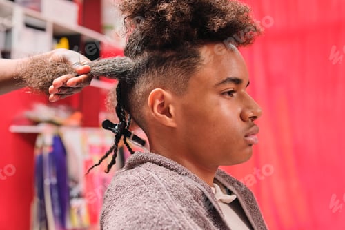 Preview: Afro young man getting braids with top hair loose and bottom braided from side view