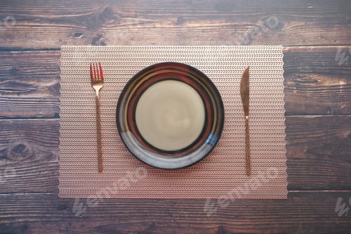 Preview: cutlery and empty plate on wooden background top down