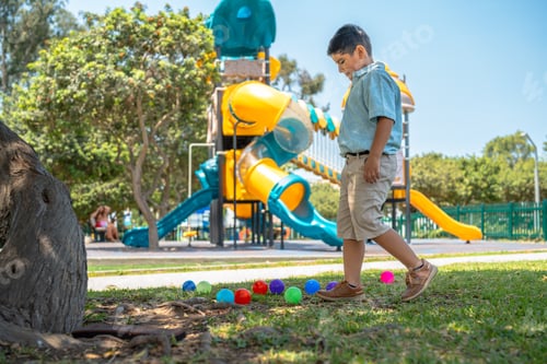 Preview: Schoolboy playing with colorful balls in a playground