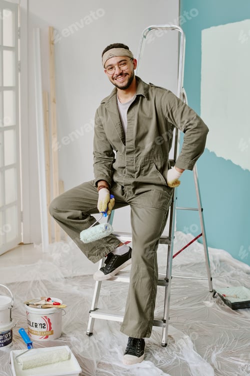 Preview: Young Adult Man Smiling While Painting Wall during Home Renovation