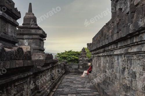 Preview: A woman sitting on stone steps in old buddhist temple setting during daylight