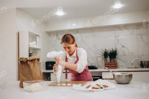 Visualização: Mulher confeiteira no interior da cozinha enche a sacola de confeitaria com creme recém-preparado.