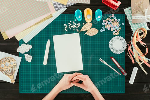 Preview: cropped image of designer sitting at table with empty white sheet of paper