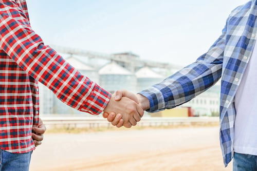 Preview: Businessmen shake hands against silos. Agriculture business
