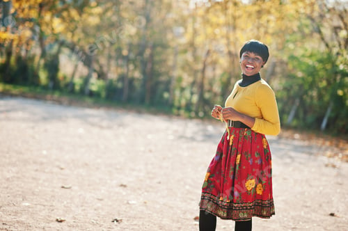 Preview: African american girl at yellow and red dress at golden autumn fall park.