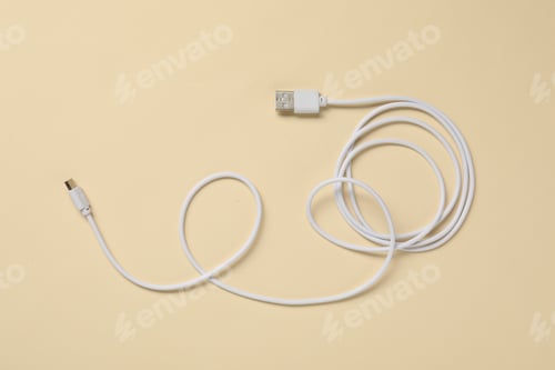 Preview: One USB charge cable on beige background, top view
