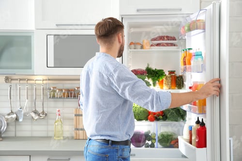 Preview: Man choosing food from refrigerator in kitchen