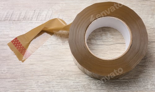 Preview: Roll of brown tape on a wooden table, top view