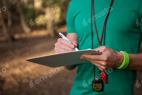 Preview: Trainer holding notepad in his hands in the forest on a sunny day