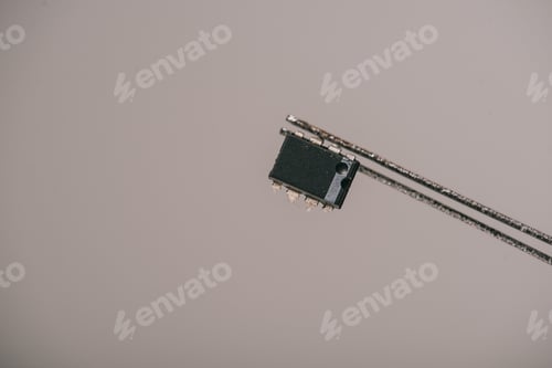 Preview: metallic tweezers with small microchip on grey background