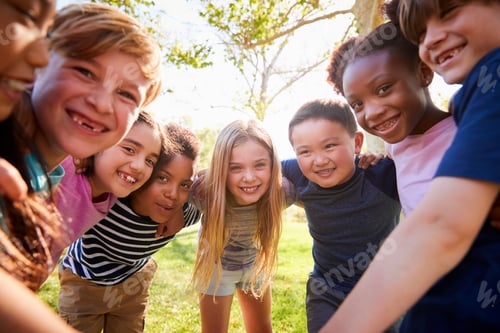 Preview: Group of smiling schoolchildren lean in to camera embracing