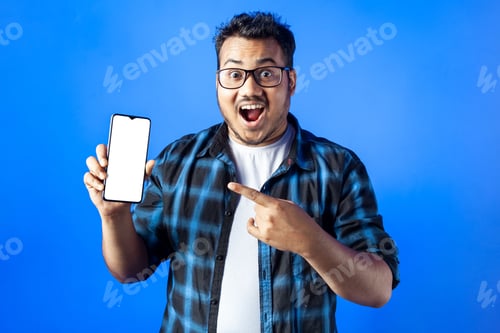 Preview: Amazed joyful Caucasian pointing finger towards smart phone with blank white screen