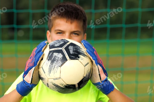 Preview: Portrait of a young goalkeeper with a soccer ball close-up