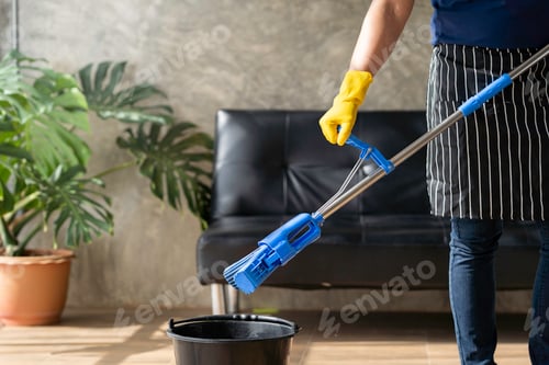 Preview: A young butler cleans the floor, mops the floor, carries a mop and a plastic bucket with brushes, gl