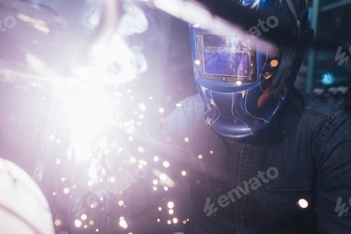 Preview: Mature man in garage, working on motorcycle, using welding equipment