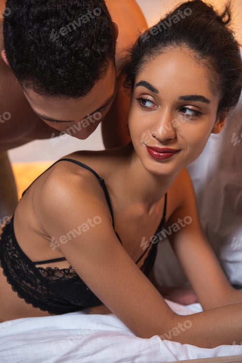 Preview: Man kissing hot african american woman on bed in bedroom