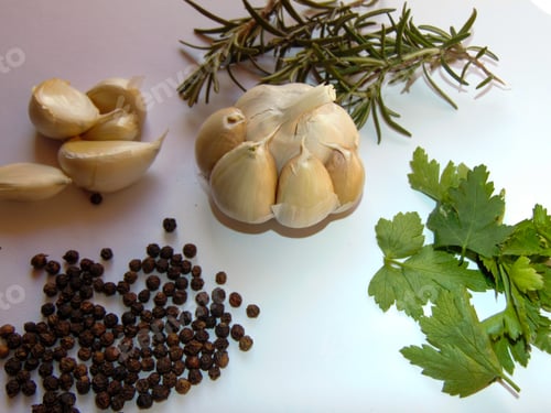 Garlic, Herbs, and Black Peppercorns on White Surface